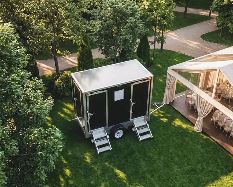 Restroom trailer positioned beside a garden and outdoor deck