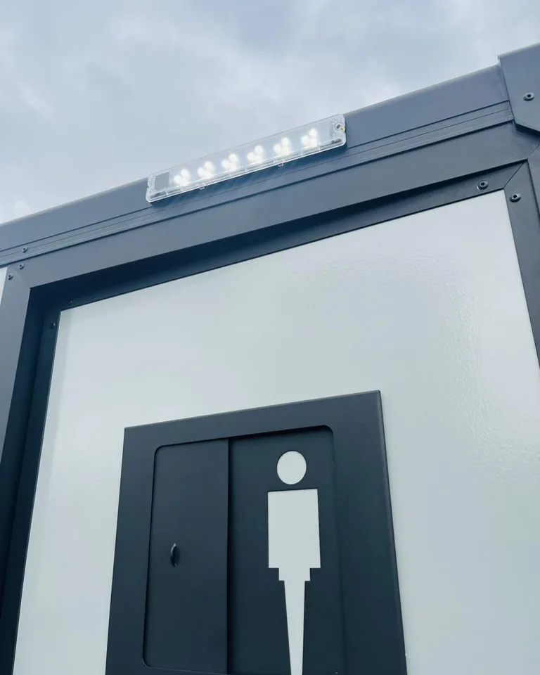 Restroom trailer exterior with an entrance sign beside the door