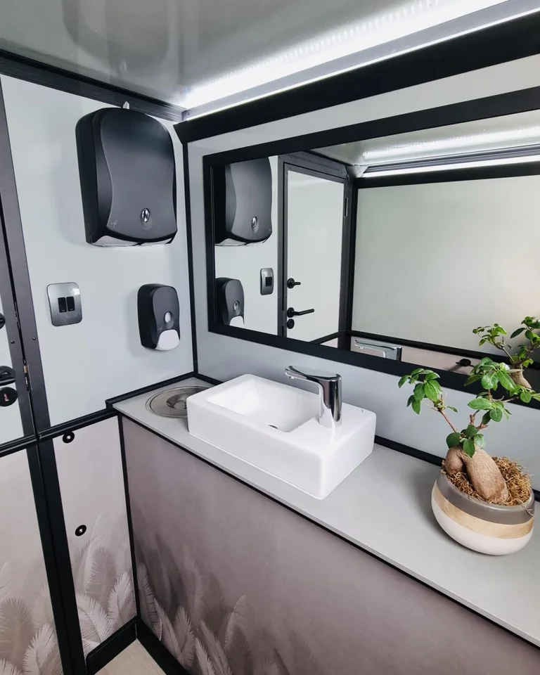Restroom trailer vanity with a white sink and large mirror