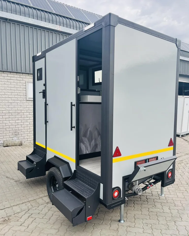 Compact restroom trailer with its entry door open and stairs extended