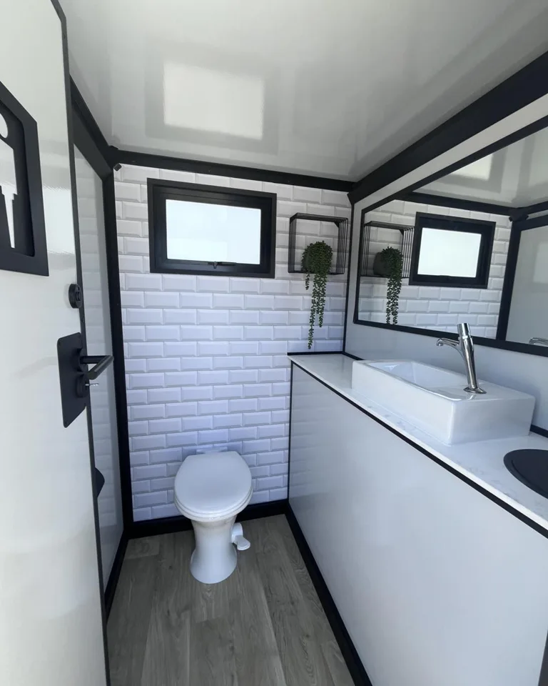Restroom trailer toilet and long vanity below small windows
