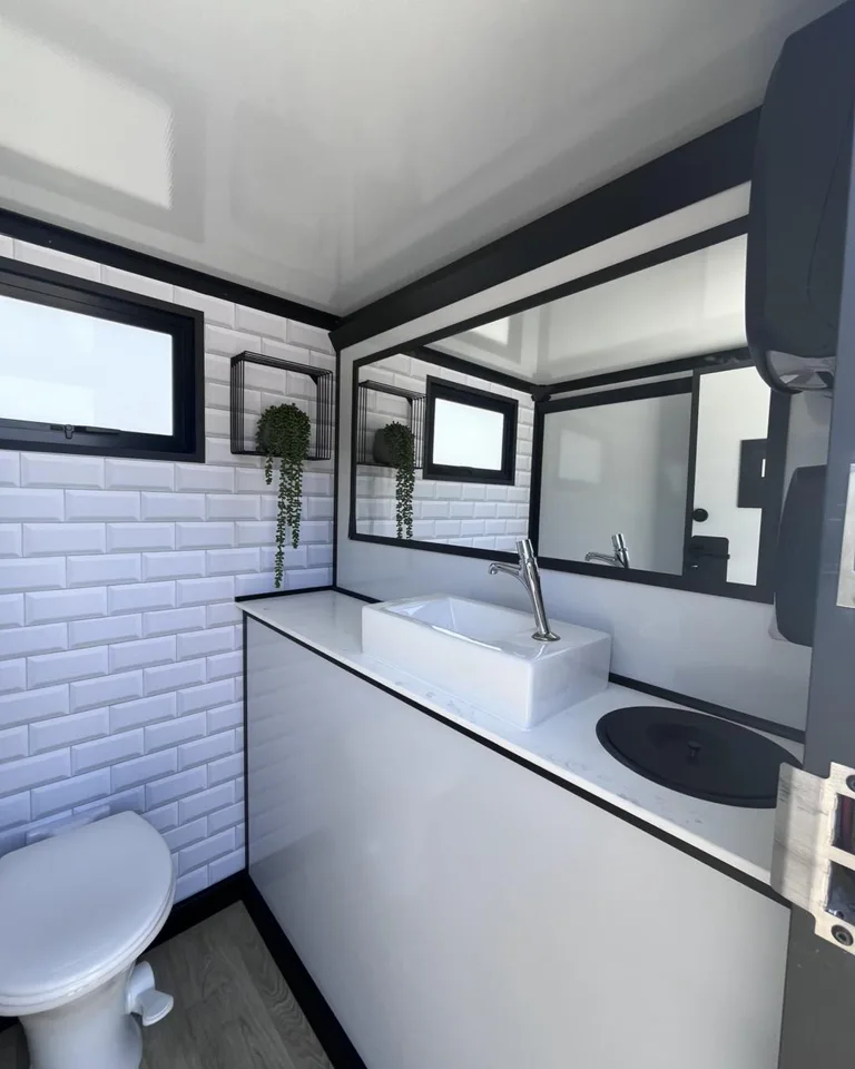 Interior vanity and toilet in a white-paneled restroom trailer