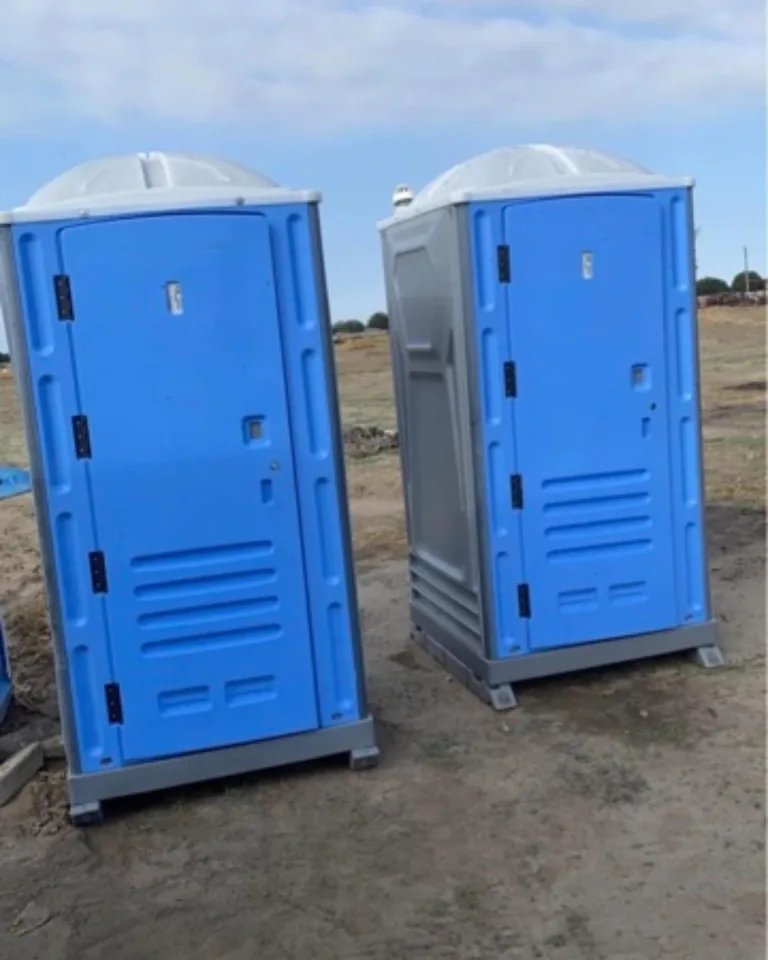 Two blue portable toilets standing on a gravel surface