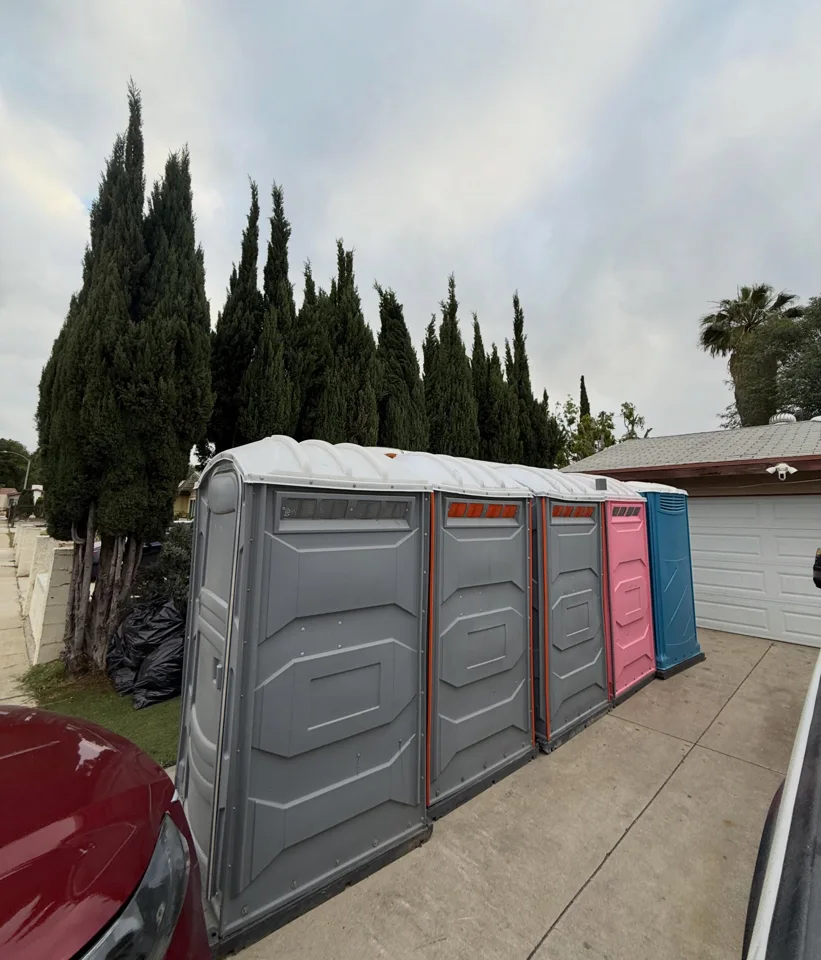 Row of wide gray portable restrooms beside standard units