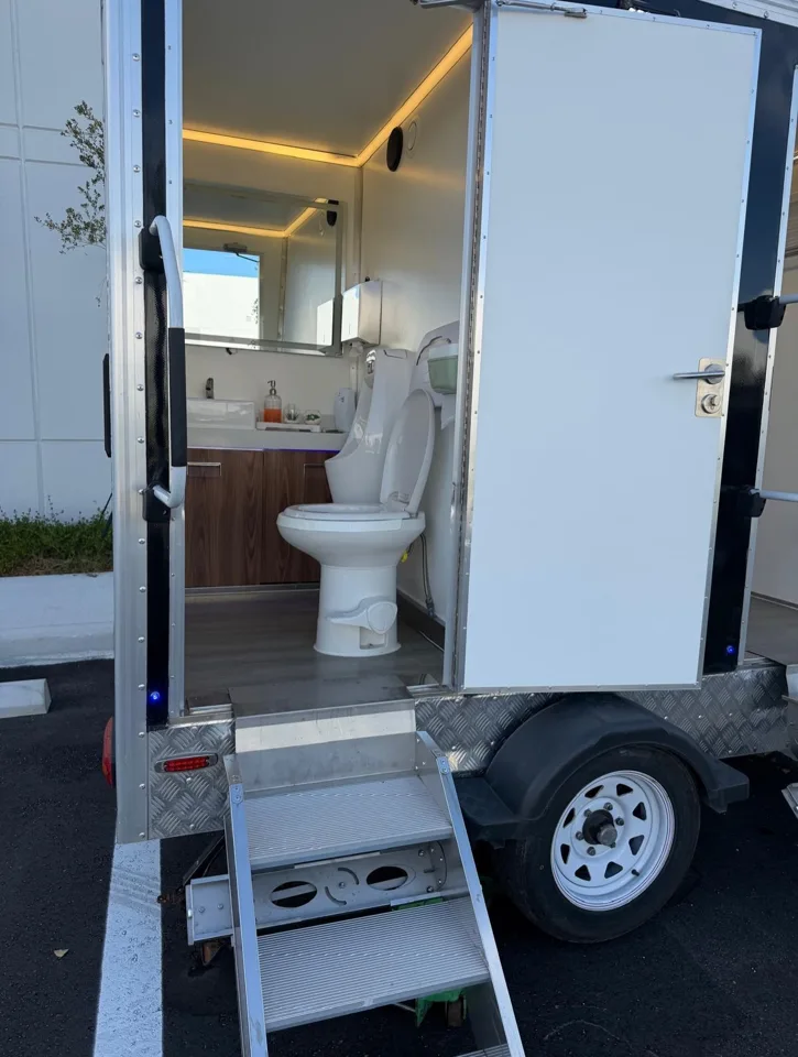Open restroom trailer doorway showing an illuminated interior