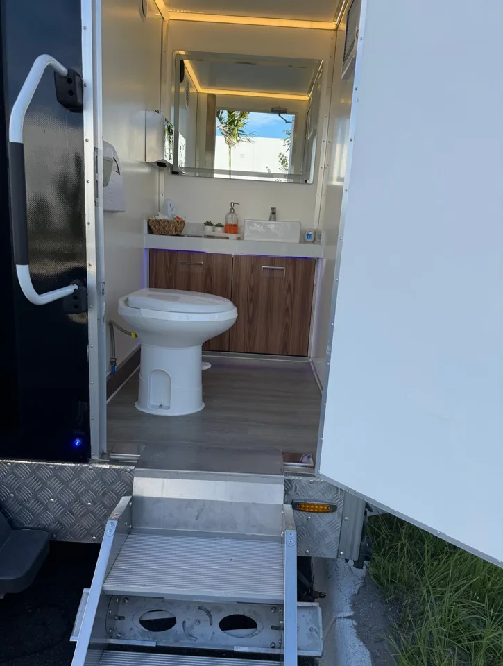Restroom trailer entrance with steps leading to a toilet and vanity
