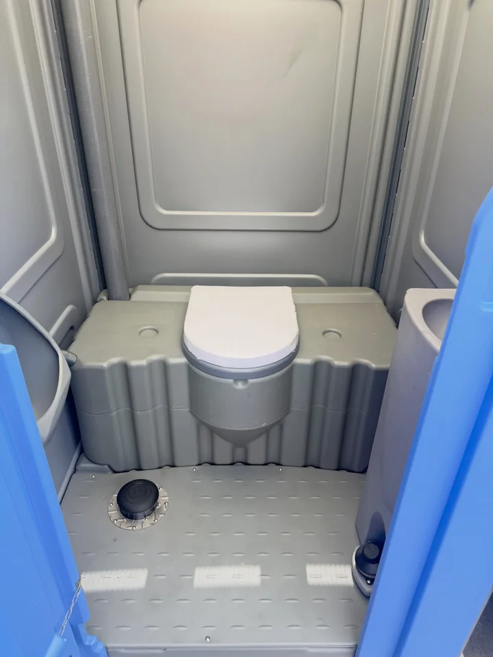 Gray portable toilet interior with a blue door frame