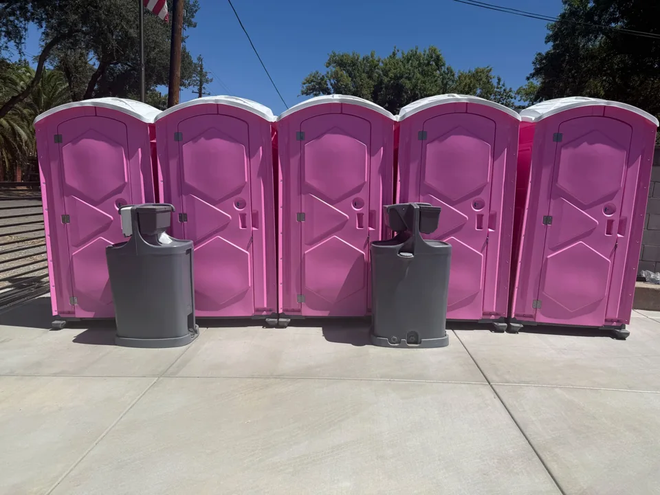 Pink portable toilets paired with two outdoor handwashing stations