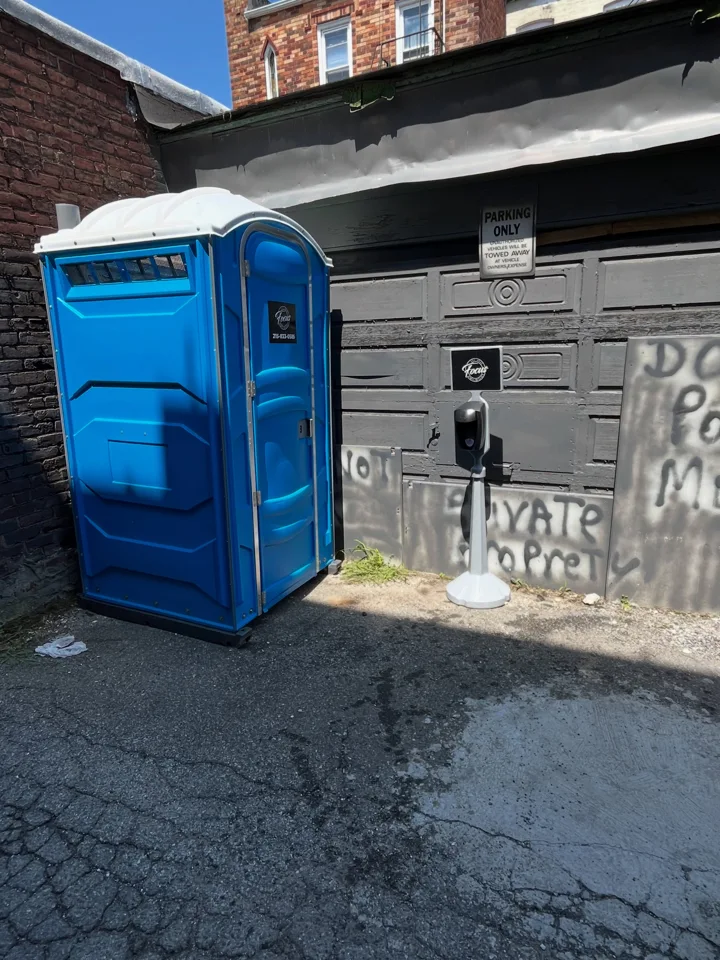 Blue portable toilet next to a house and patio